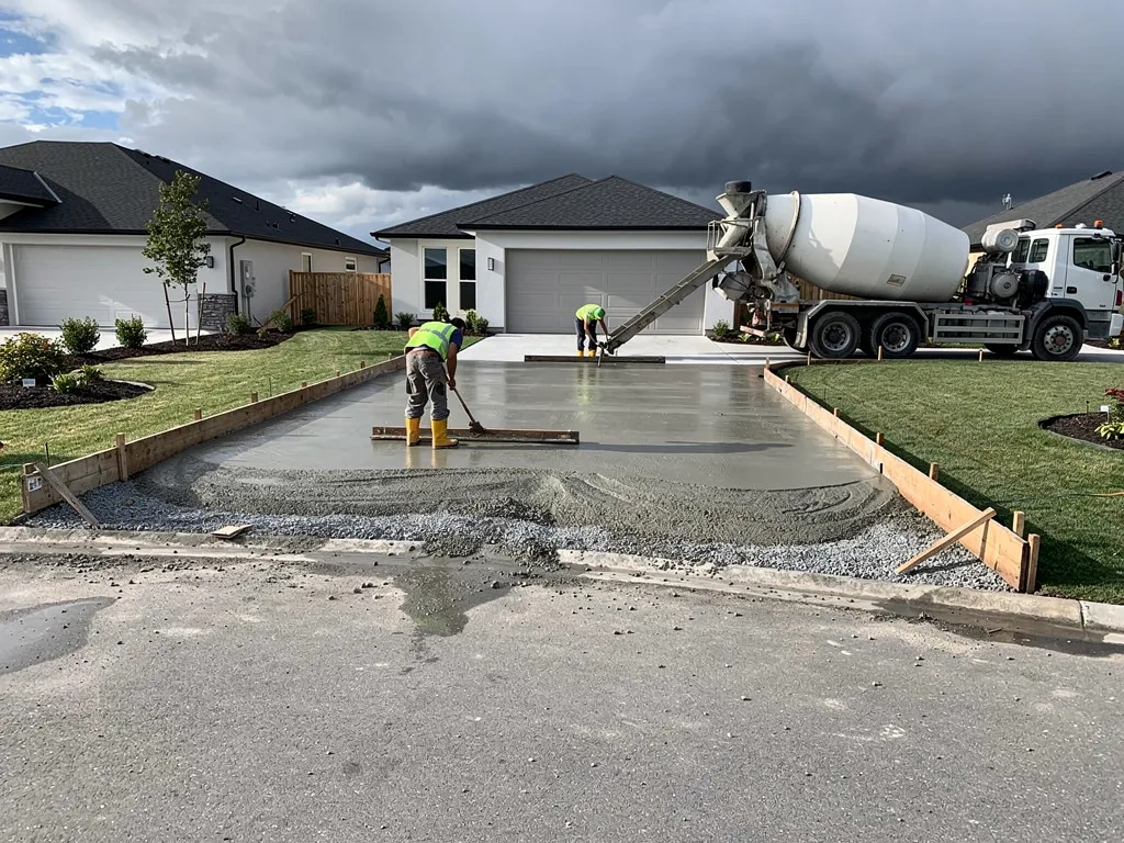 Wooden forms set along driveway edges with concrete being poured